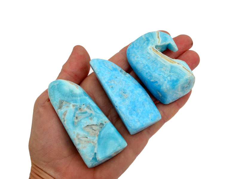 Three small blue aragonite free form stones 40mm-50mm on hand with white background