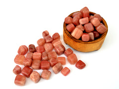 Several rose calcite tumbled crystals inside a wood bowl and several crystals outside