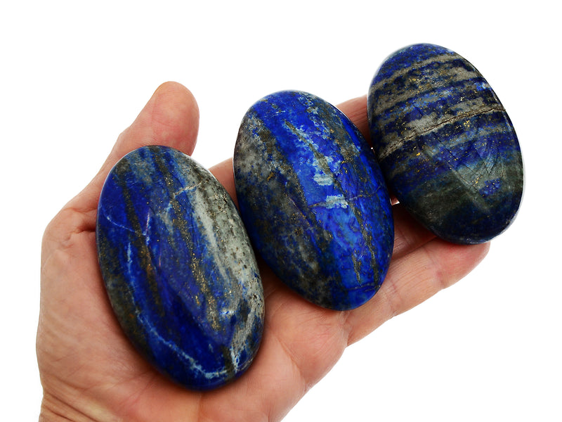 Three lapis lazuli palm stone crystals 55mm-75mm on hand with white background