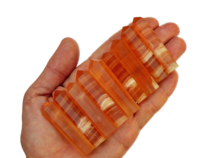 Nine small honey calcite crystal points 55mm on hand with white background