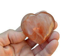 One fire quartz heart stone50mm on hand with white background