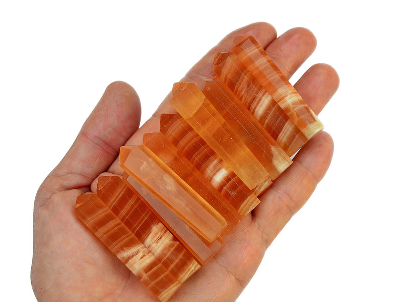 Ten honey calcite faceted crystal points 55mm on hand with white background