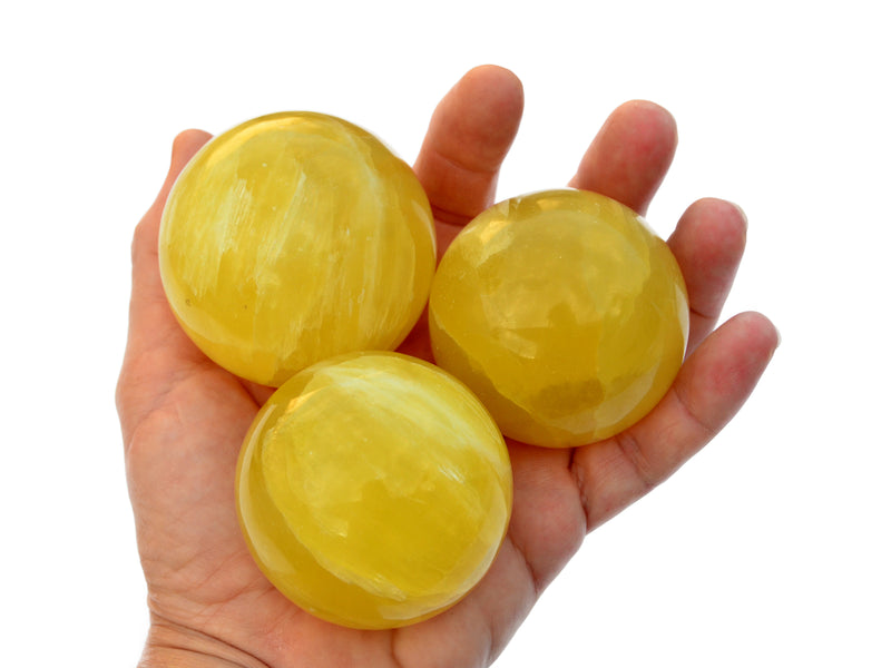 Three lemon calcite crystal balls 55mm on hand with white background