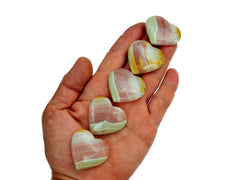 Five pink banded onyx shapped heart crystals 30mm on hand with white background