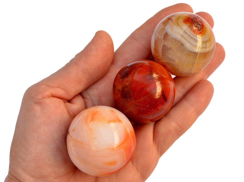 Three carnelian crystal spheres 25mm-35mm on hand with white background