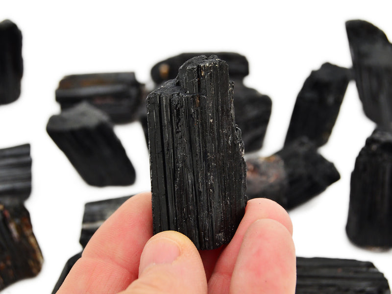 One rough black tourmaline cathedral 45mm on hand with background with some crystals on white