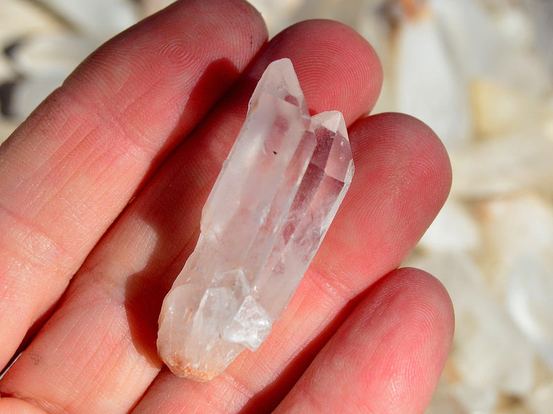One mini raw crystal point on hand with background with several points