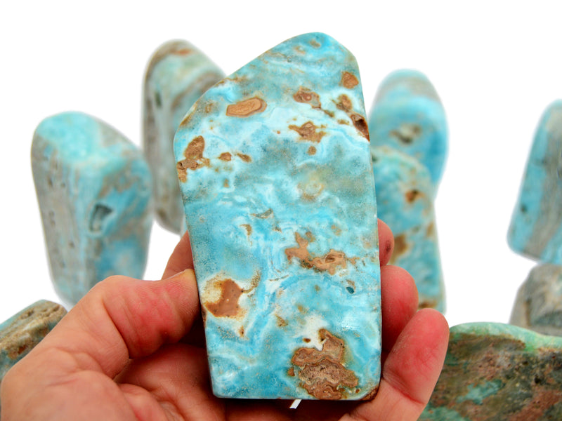 One big blue aragonite free form mineral 100mm on hand with background with some crystals on white