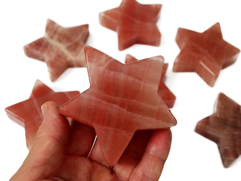 One rose calcite star mineral 80mm on hand with background with some stars on white