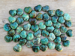 Several green chrysocolla heart shapped minerals 30mm on wood table