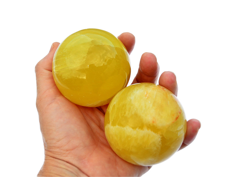 Two lemon calcite sphere crystals 65mm on hand with white background