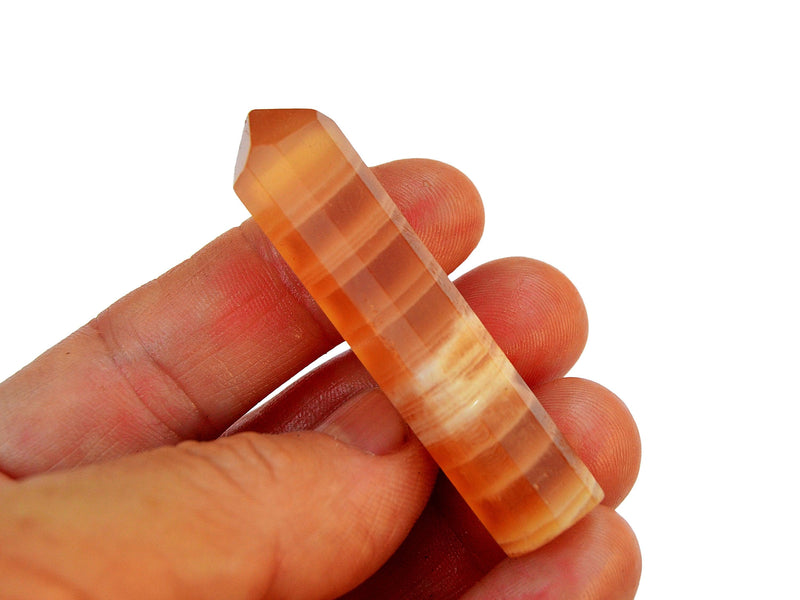 One banded honey calcite crystal point 55mm on hand with white background