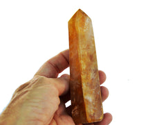 One golden healer faceted point crystal 100mm on hand with white background
