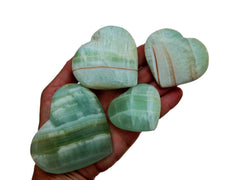 Four banded pistachio calcite crystal hearts 40mm-80mm on hand with white background