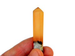 One honey calcite crystal point 55mm on hand with white background