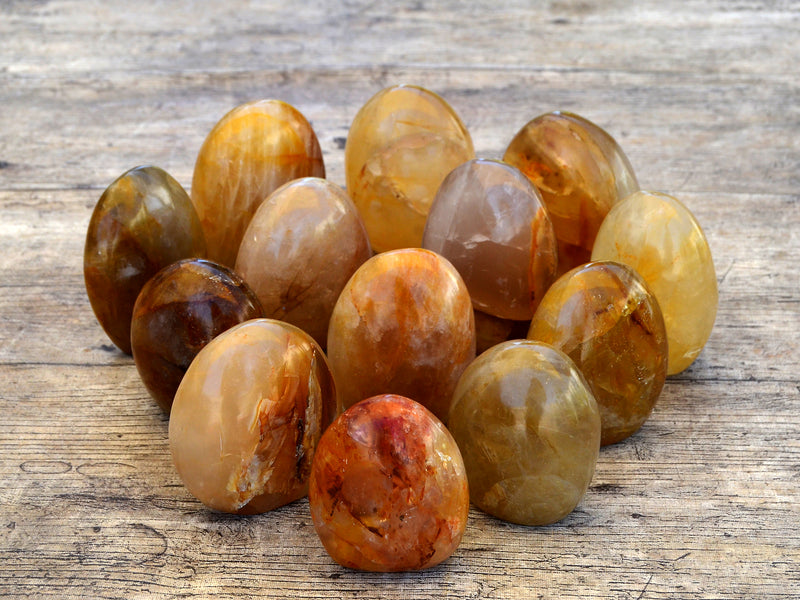 Several yellow hematoid quartz free form stones on wood table