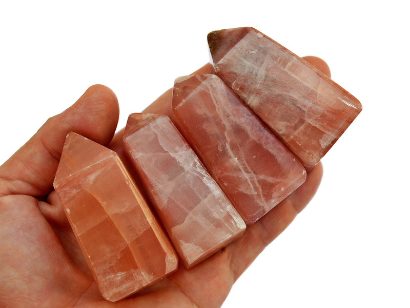 Four rose calcite crystal obelisks 55mm-60mm on hand with white background