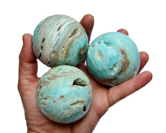 Three blue aragonite spheres 65mm-70mm on hand with white background