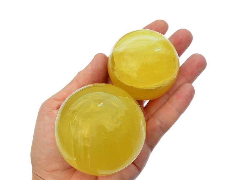 Four lemon calcite sphere minerals 50mm-65mm on hand with white background