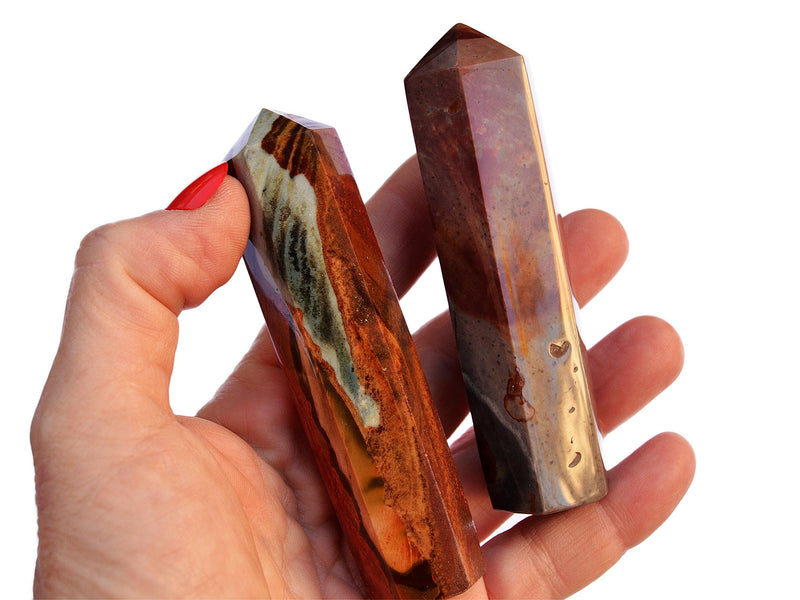 Two polychrome jasper crystal obelisks 90mm on hand with white background