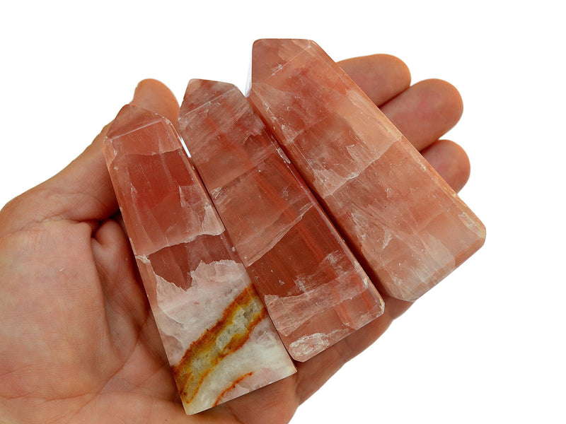 Three rose calcite crystal towers 80mm-85mm on hand with white background