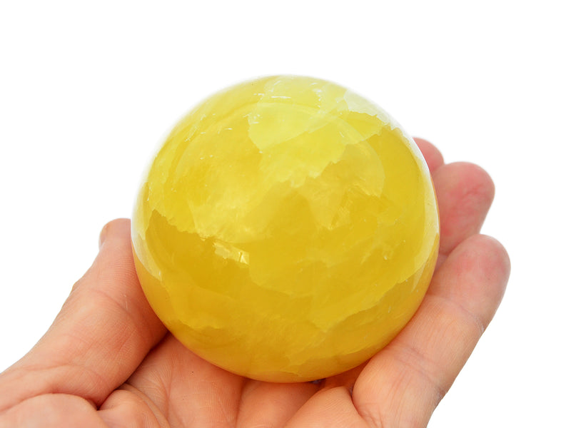 One lemon calcite sphere stone 60mm on hand with white background