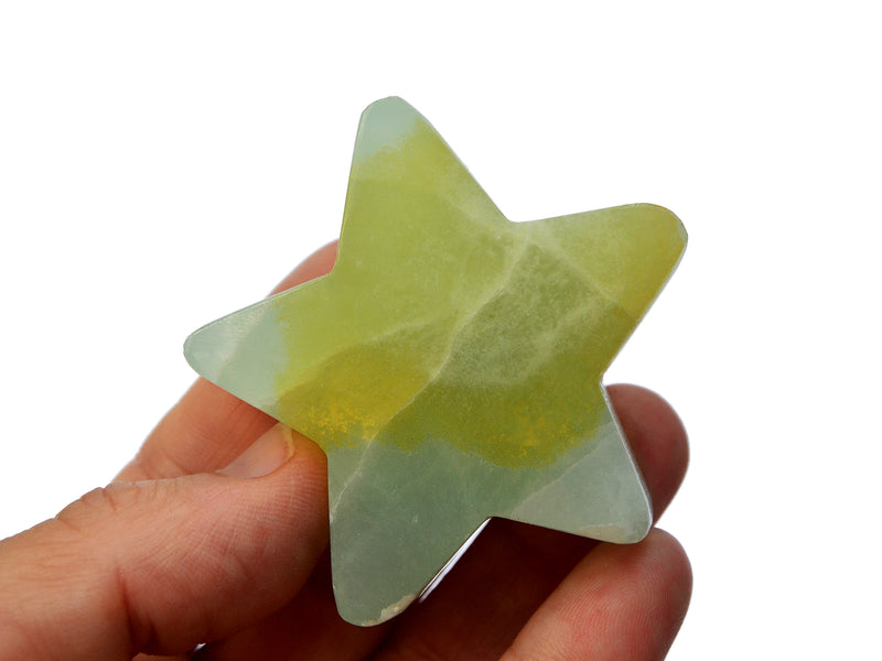 One yellow green pistachio calcite star shapped crystal 60mm on hand with white background