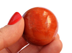 One orange carnelian crystal ball 30mm on hand with white background