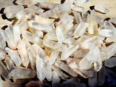 Several mini raw crystal quartz points on wood table