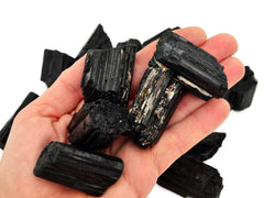 Five rough black tourmaline cathedral stones 35mm-45mm on hand with background with some crystals on white