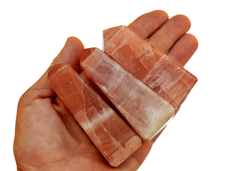 Three large rose calcite towers 80mm-85mm on hand with white background