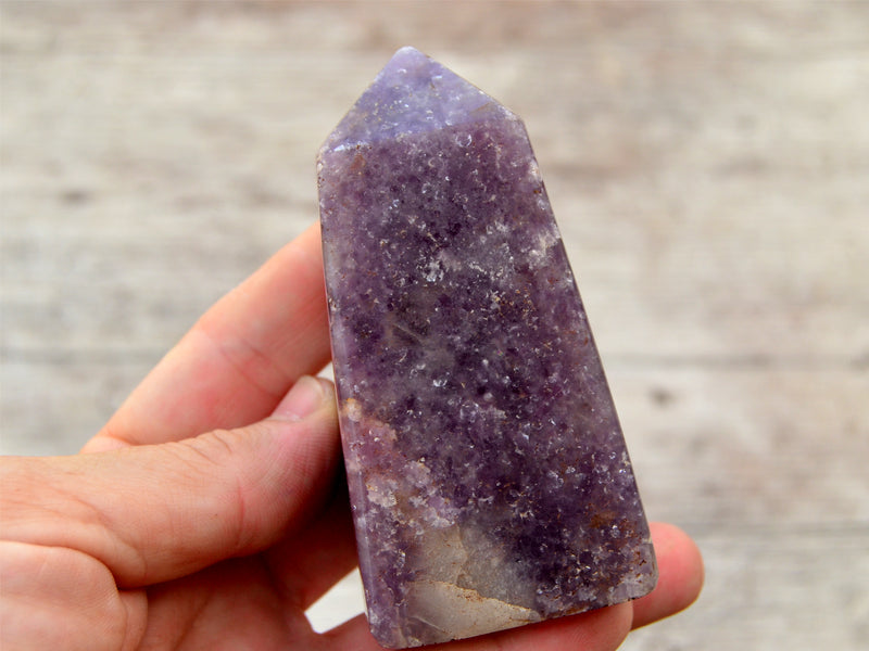 One chunky purple lepidolite crystal obelisk 80mm on hand with white background