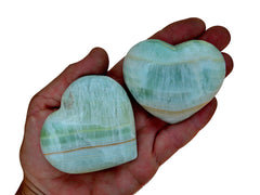 Two green pistachio calcite crystal stones 60mm-70mm on hand with white background