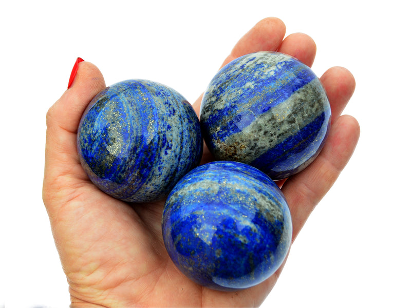 Three lapis lazuli sphere crystals 55mm on hand with white background