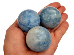 Three blue calcite spheres 35mm-40mm on hand with white background