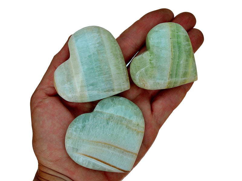 Three banded pistachio calcite crystal hearts 60mm-70mm on hand with white background