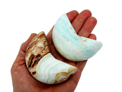 Two blue caribbean calcite moon stones 75mm on hand with white background