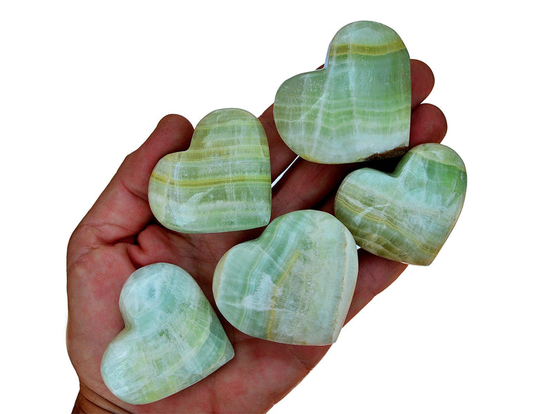 Five banded pistachio calcite heart stones 40mm-50mm on hand with white background