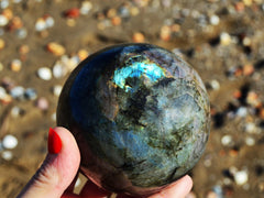 One large labradorite sphere 70mm on hand with sun  background