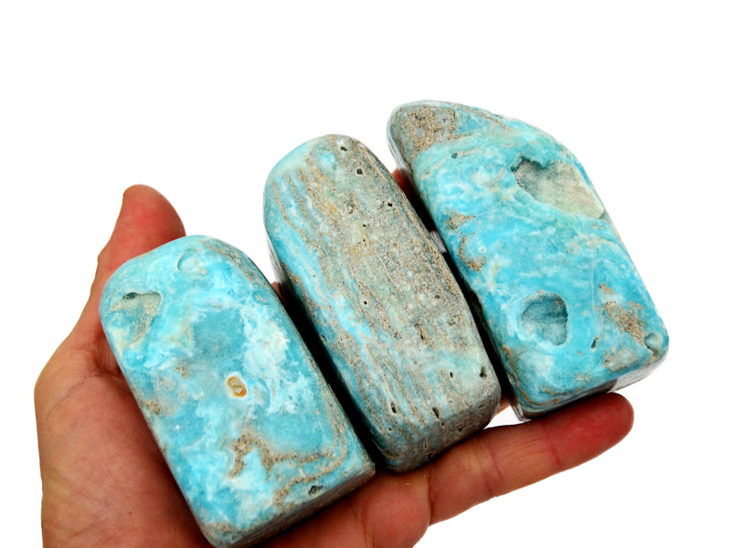 Three blue aragonite free form minerals 60mm-70mm on hand with white background