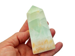 One large aqua blue green caribbean calcite tower on hand with white background