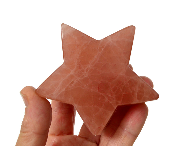 One large rose calcite star shapped crystal 78mm on hand with white background