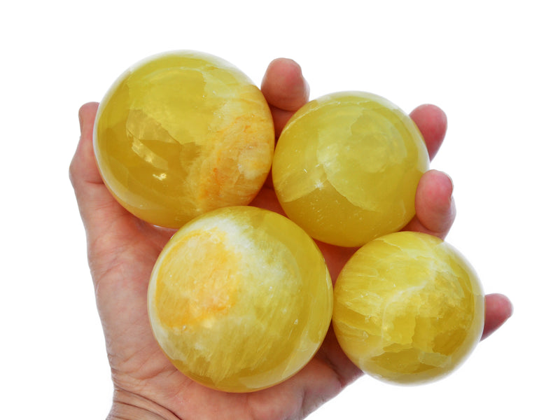 Four lemon calcite crystal balls 50mm-65mm on hand with white background