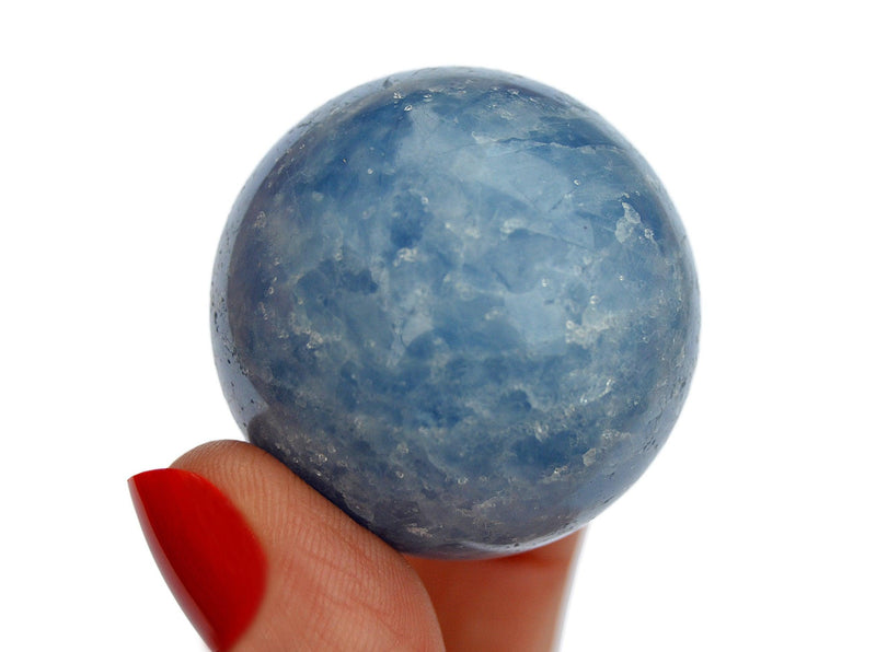 One blue calcite sphere crystal 30mm on hand with white background