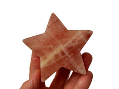 One rose calcite star shapped crystal 80mm on hand with white background