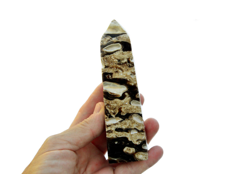 One druzy chocolate calcite obelisk 100mm on hand with white background