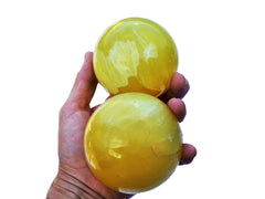 Two lemon calcite sphere crystals 65mm-80mm on hand with white background
