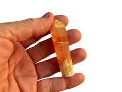 One honey calcite faceted crystal point 55mm on hand with white background