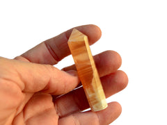 One honey calcite  small crystal tower 60mm on hand with white background