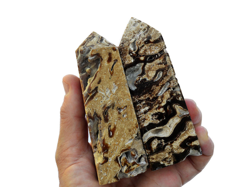 Two natural druzy chocolate calcite towers 110mm on hand with white background